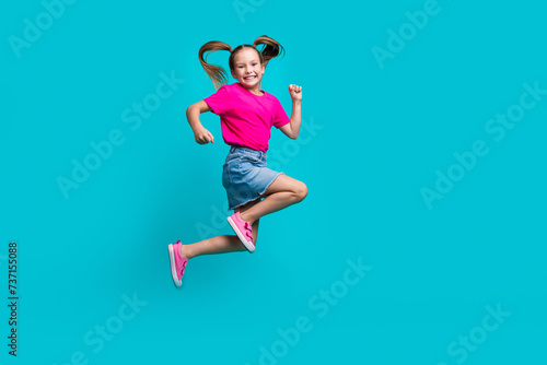 Full length photo of good mood flying girl wear stylish t-shirt denim skirt run shopping to empty space isolated on teal color background