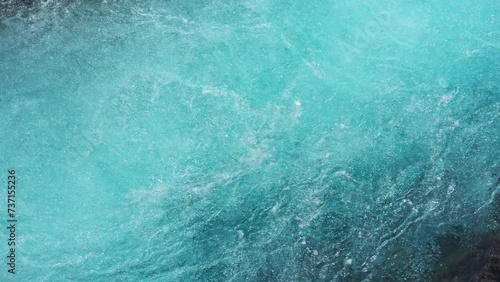 Natural crystal blue water rapids with air bubbles flowing down from the waterfall