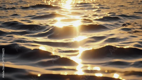 The glimmering surface of the ocean reflecting the golden light of the sun creating a mirrorlike effect.