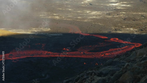 Lava river flowing down the mountain to the city. Boiling magma. Volcanic eruption in Iceland. photo