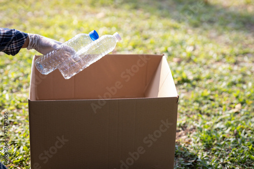 Close-up of a young volunteer collecting plastic bottles into a bin for recycling. The concept of loving the world and the environment