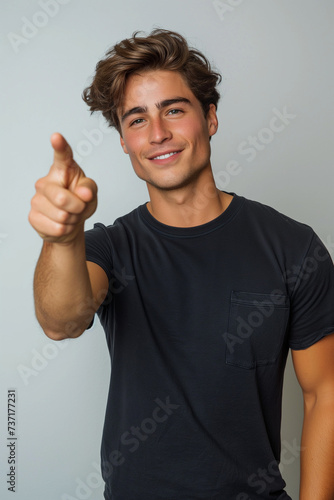 Young man on white background pointing ahead with a smile. Jeune homme sur fond blanc montrant du doigt devant lui avec le sourire.