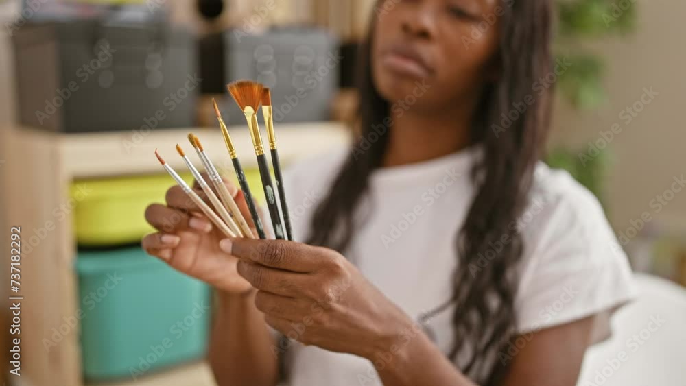 Close-up of an african woman artist holding paintbrushes indoors focusing on her creative expression Close-up of an african woman artist holding paintbrushes indoors focusing on her creative expression