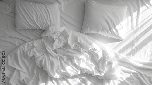 a black and white photo of a bed with a white comforter on top of it and pillows on the bottom of the bed.