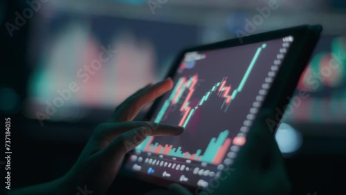 Person analyzing stock market graph on a tablet touchscreen. Close up, slow motion. 