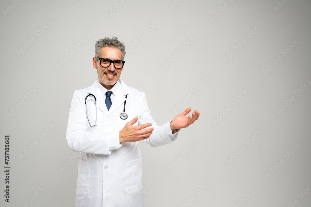 A mature doctor with a warm smile extends his hand in a welcoming gesture, set against a light backdrop, evoking a sense of friendliness and openness that's vital for patient relations. A mature doctor with a warm smile extends his hand in a welcoming gesture, set against a light backdrop, evoking a sense of friendliness and openness that's vital for patient relations.