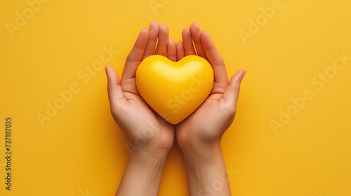 Female hands on a yellow background hold a yellow heart