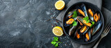 Cooked mussels with parsley and lemon on a black table. Seafood