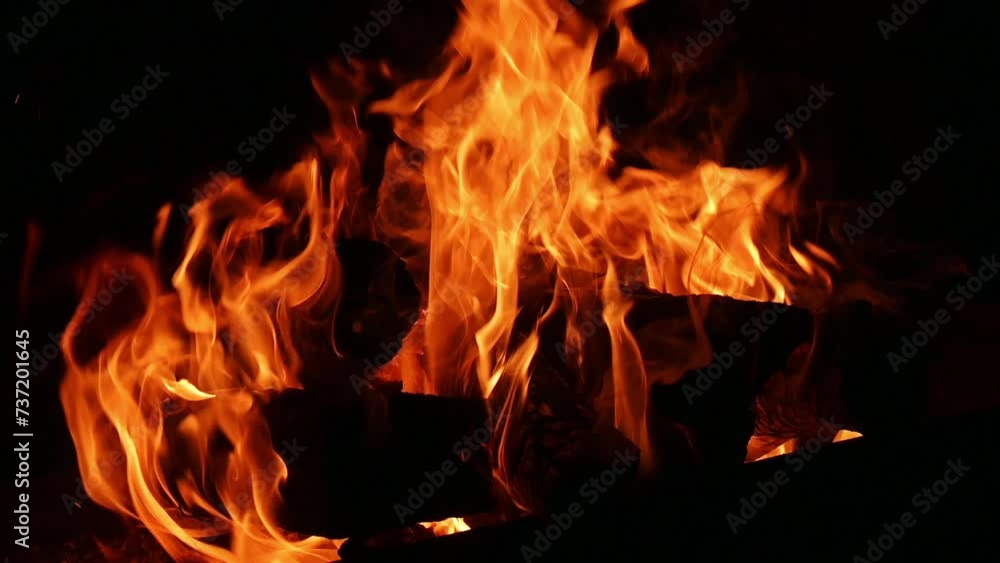 Fire flames of a bonfire on a black background in slow motion. Fire flames of a bonfire on a black background in slow motion.