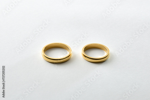 Engagement gold rings side by side on white textured base