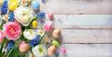 Colorful spring flowers with easter eggs on rustic light wooden planks with copy space for your text. Celebration concept, greeting card