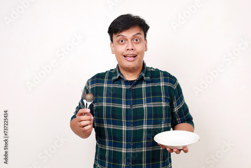 Young asian man showing happy expression while holding an empty plate photo