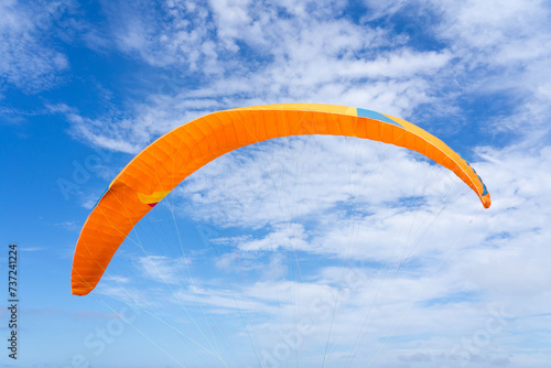Orange paragliding sail with a blue sky background with copy space