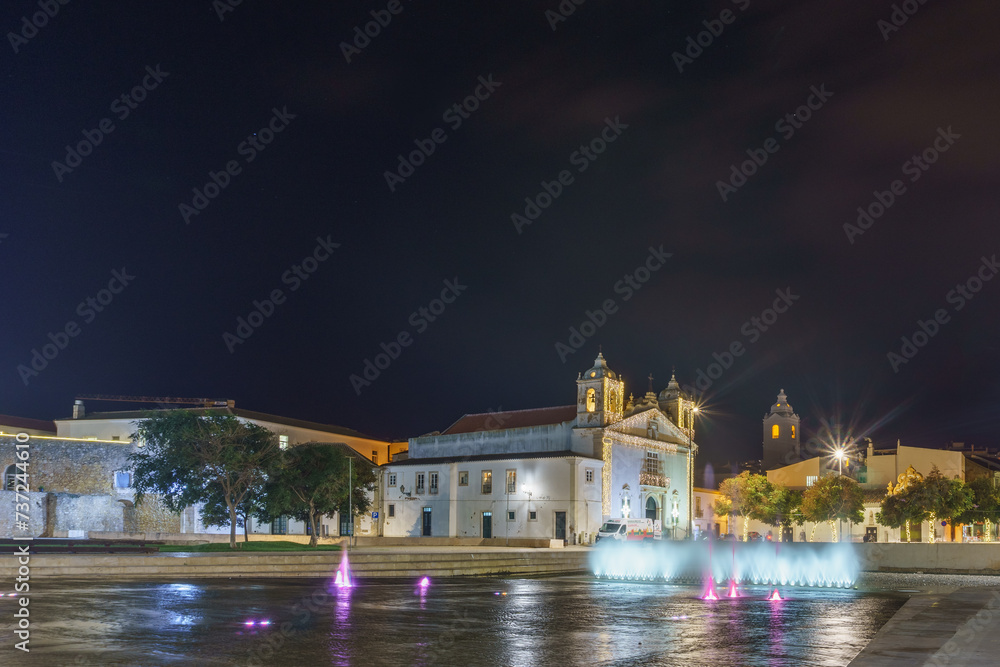 Urban landscape at night with Catholic Church Igreja de Santa Maria with fountain in front in Lagos, Algarve, Portugal
