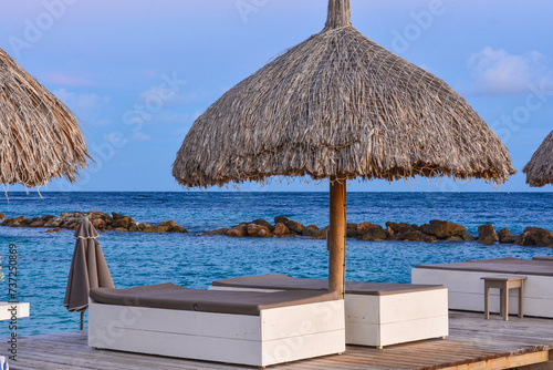 Fototapeta Naklejka Na Ścianę i Meble -  Palapa parasols and sun loungers on the jetty at the beach resort hotel on tropical Curacao island. 