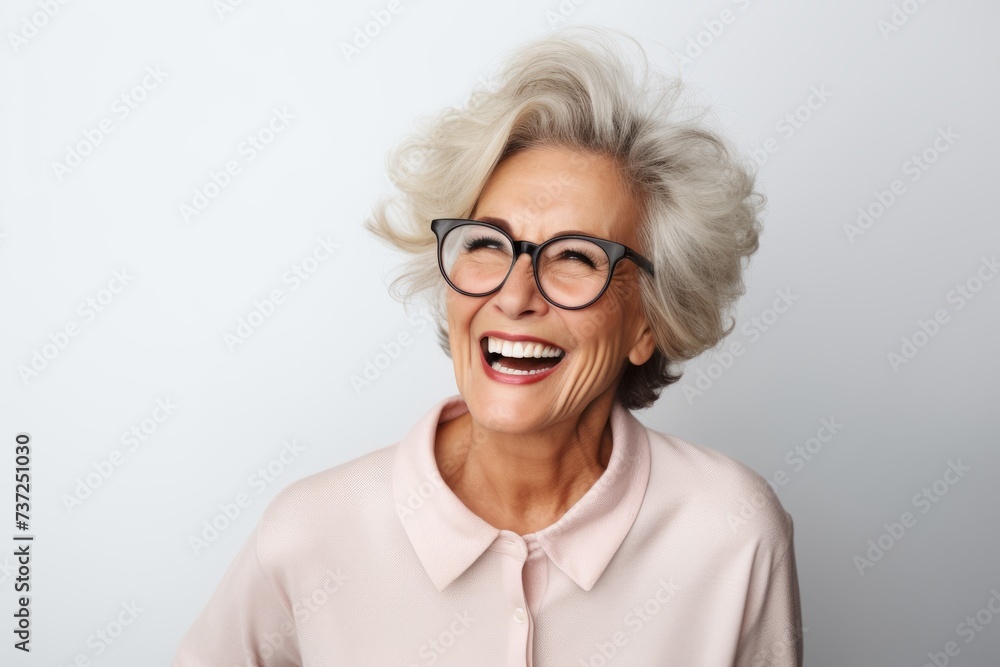 Portrait of a happy senior woman with eyeglasses against grey background
