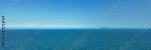 Serene ocean view with distant mountains under a clear blue sky, perfect for travel and vacation-themed designs