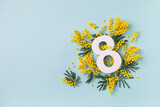 International Women Day on 8 March celebration with fresh spring mimosa flowers and number eight top view. Beautiful holiday greeting background with copy space.
