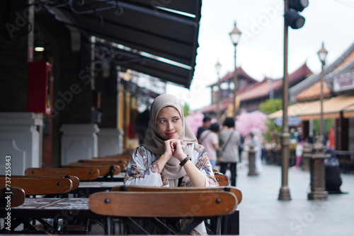 Serene Contemplation concept. Indonesian Hijabi Woman Lost in Thought at Cafe Bench photo