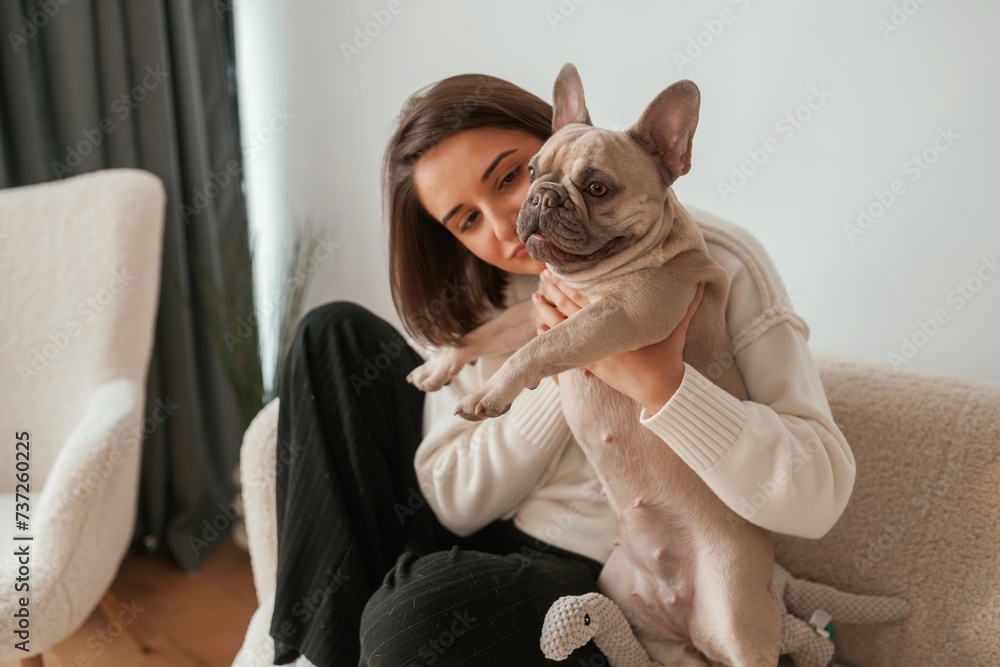 Conception of love and care. Young woman is with her pug dog at home