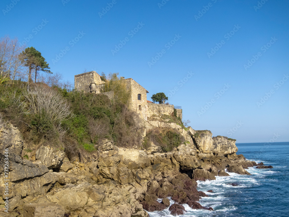 Panoramic view of the castle in the tourist town of Hondarribia on the cliffs above the sea on a sunny day in the Basque country. 
san telmo castle in Fuenterrabia