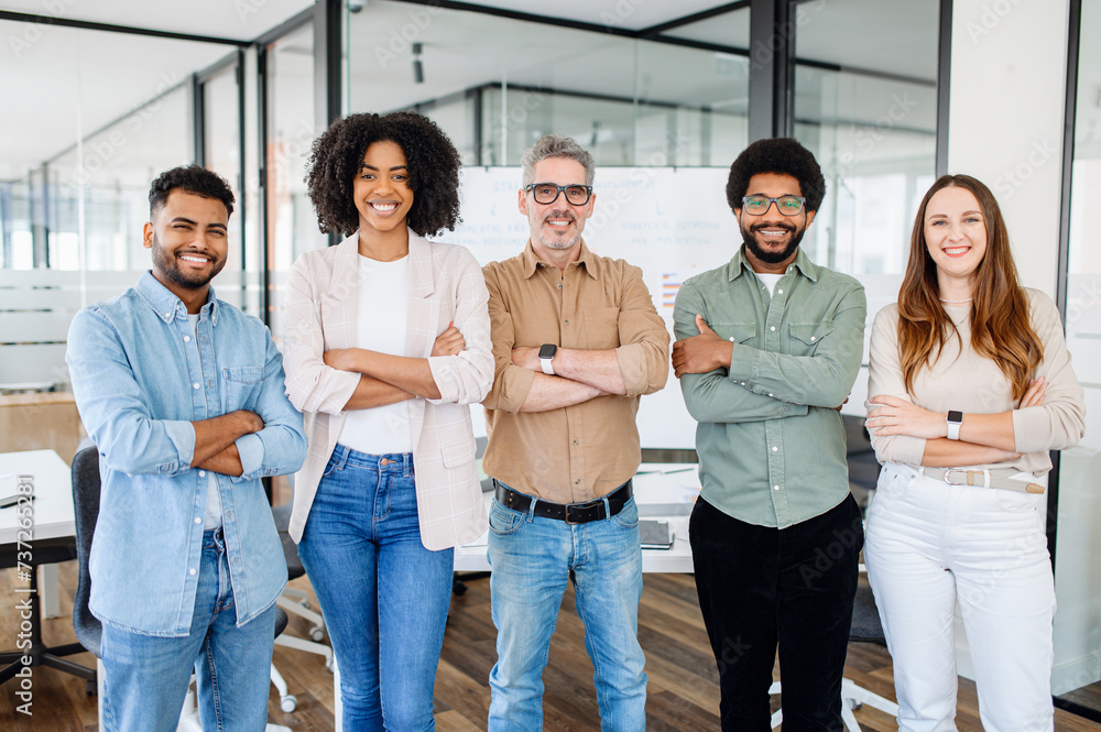 © Vadim Pastuh - A dynamic team of five, radiating positivity and diversity, stand confidently in co-working space, the seasoned team leader at center, exemplifying unity and successful collaboration in the workplace. © Vadim Pastuh - A dynamic team of five, radiating positivity and diversity, stand confidently in co-working space, the seasoned team leader at center, exemplifying unity and successful collaboration in the workplace.