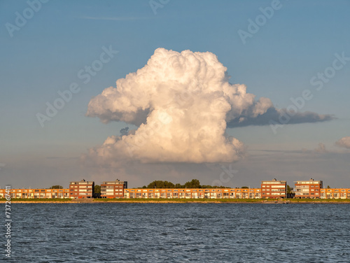 Towering cumulonimbus cloud over apartments on IJsselmeerdijk in Lelystad, Netherlands photo