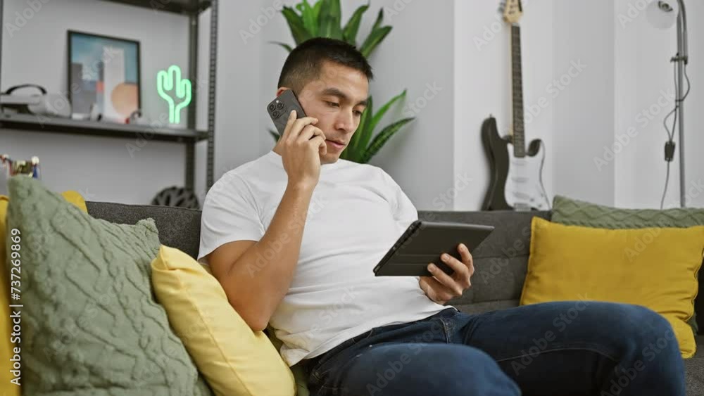 A hispanic man multitasks with a phone call and tablet in a cozy living room setting, exuding a casual, modern lifestyle. A hispanic man multitasks with a phone call and tablet in a cozy living room setting, exuding a casual, modern lifestyle.