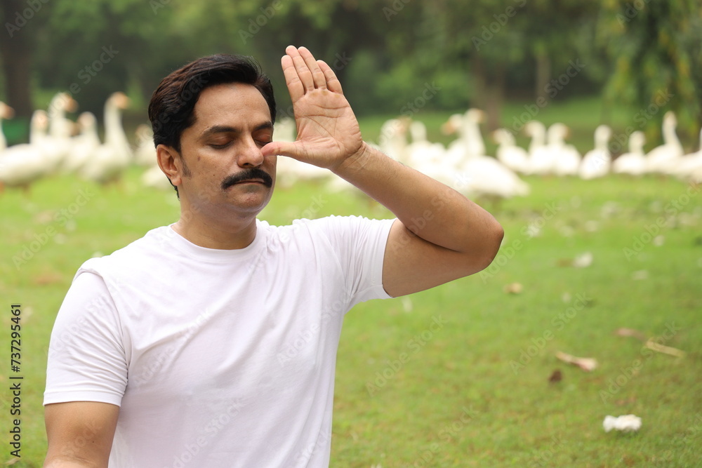 Happy Indian man doing yoga early morning in a tranquil environment surrounded with lush green serene atmosphere. high concentration level. Anulom vilom Happy Indian man doing yoga early morning in a tranquil environment surrounded with lush green serene atmosphere. high concentration level. Anulom vilom