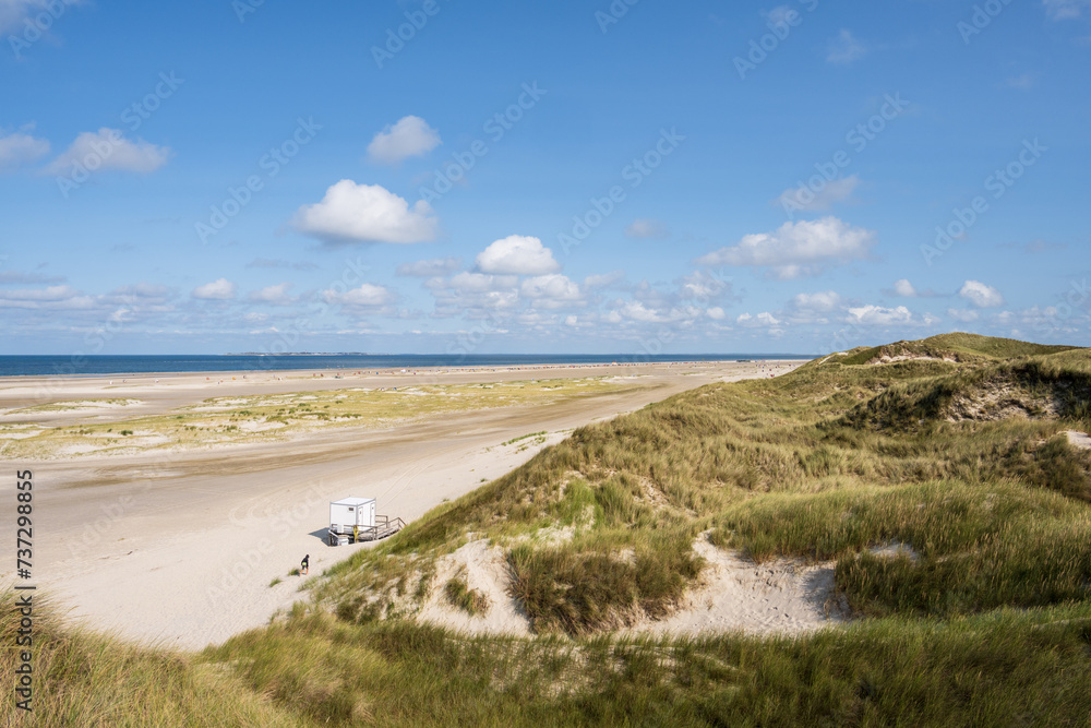 Blick aus den Dünen von Norddorf auf Amrum über den feinen breiten Sandstrand am Horizond Blick auf die Insel Sylt mit dem Leuchtturm von Hörnum