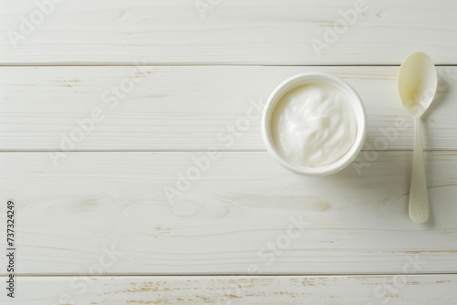 Fresh yogurt and spoon on white wooden table removing plastic cup