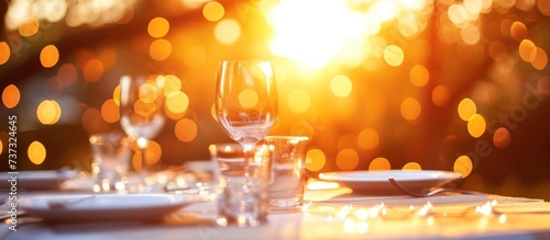 Luxury wedding dinner table set sparkling glassware and pristine white plates on sunset outdoor.