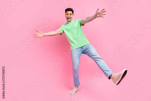 Full length photo of young friendly macho man wear green t shirt denim jeans trendy sunglasses hugs you isolated on pink color background