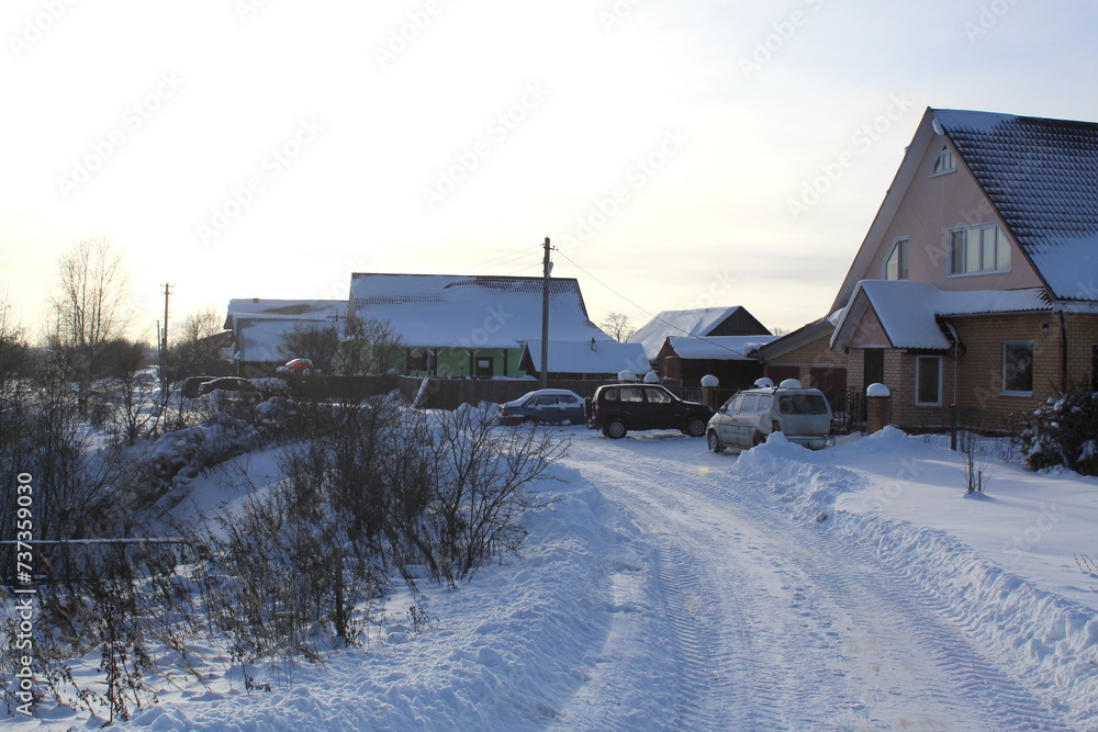 The village is covered with snow on a clear winter day.
