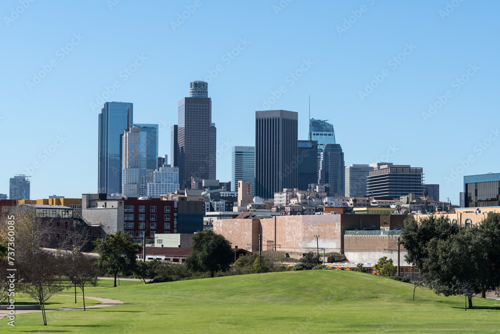 Downtown Los Angeles skyline cityscape towers with grassy park lawn in foreground.
