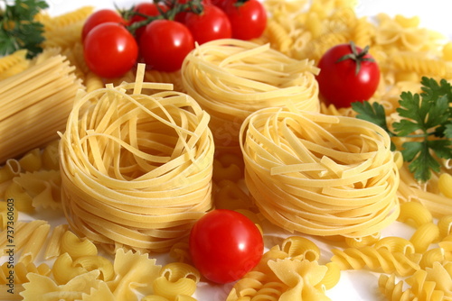  Pasta in the form of a nest with vegetables and herbs lies on a white background.