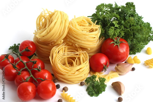 Pasta in the form of a nest with vegetables and herbs lies on a white background. 
