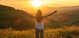 Woman with raised hands at sunset in a field. The concept of freedom and unity with nature.