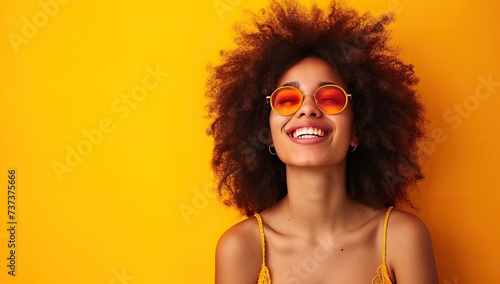 Cheerful young woman on a yellow background with sunglasses. The concept of summer and happiness.