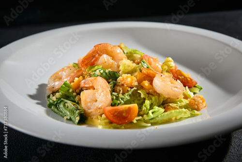 Shrimp salad with quinoa and mixed greens closeup, garnished with cherry tomatoes and a light dressing