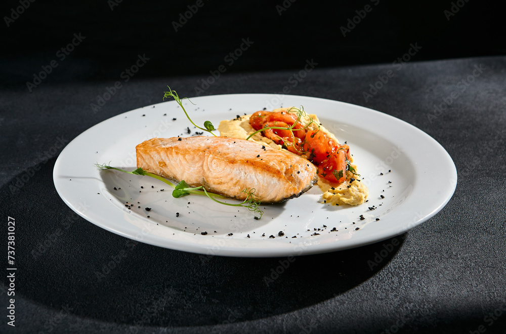 Salmon steak with hummus and tomatoes on a white plate Salmon steak with hummus and tomatoes on a white plate