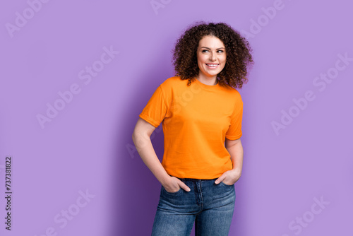Photo of cool dreamy woman wear orange t-shirt smiling looking empty space isolated purple color background