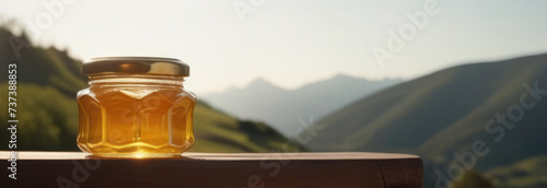 Banner Honey in a glass jar with on a wooden surface on the background of a mountain landscape. Beekeeping products. Fresh honey from honeycomb, flower honey, variegated herbs. Place for text photo