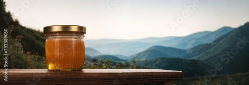 Banner Honey in a glass jar on a wooden surface on the background of a mountain landscape. Beekeeping products. Fresh honey from honeycomb, flower honey, variegated herbs. Place for text photo