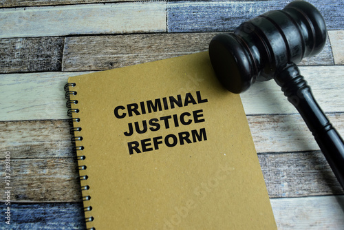 Concept of Criminal Justice Reform write on book with gavel isolated on Wooden Table. photo