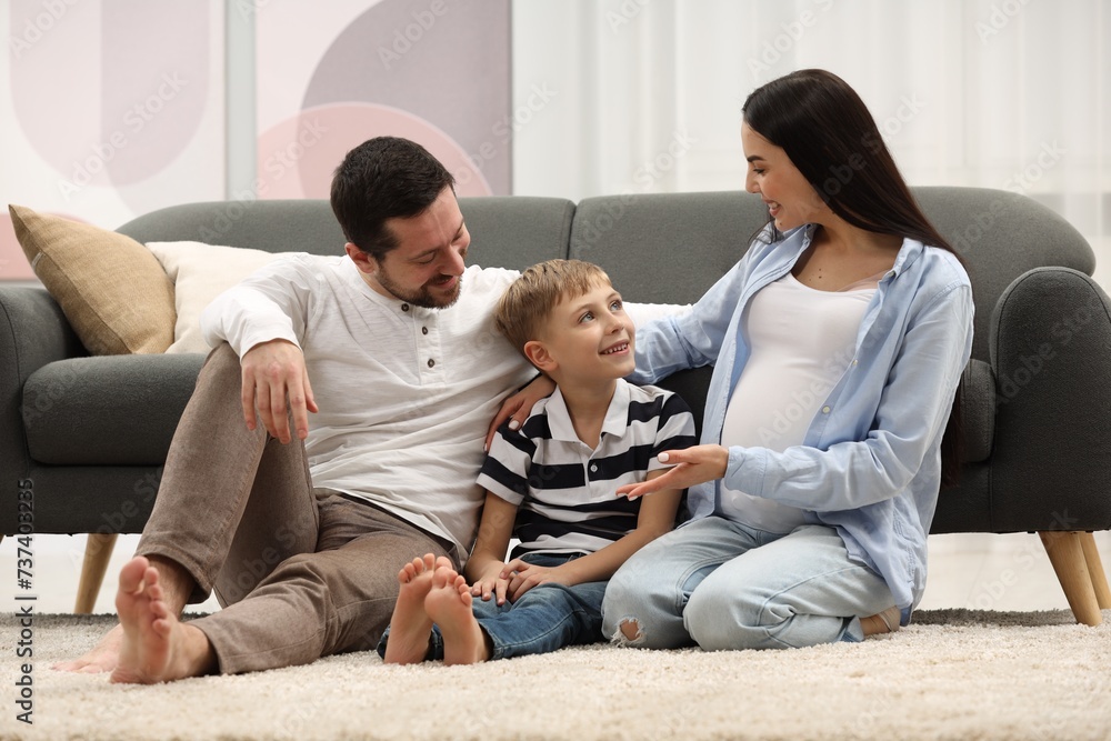 Pregnant woman spending time with her son and husband at home. Happy family