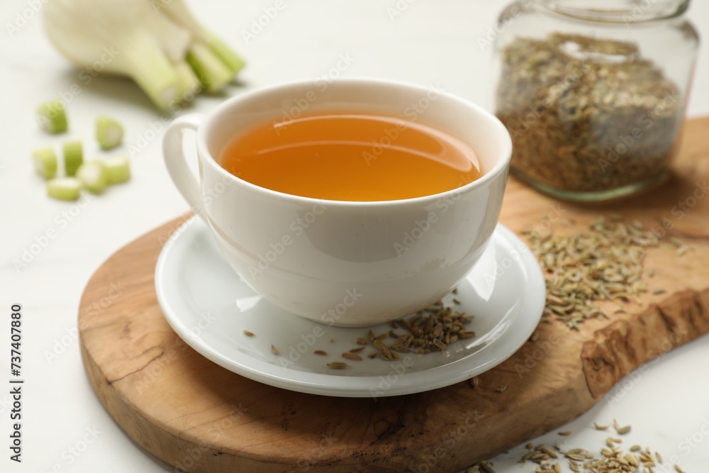Fennel tea in cup, seeds and fresh vegetable on white table, closeup Fennel tea in cup, seeds and fresh vegetable on white table, closeup