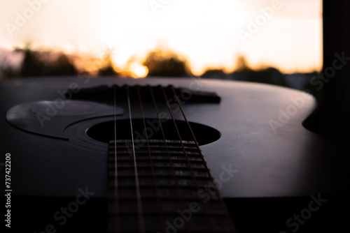 Guitar and strings on background of bright sunset