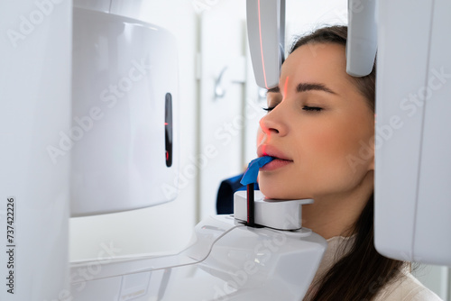 Portrait young woman having panoramic digital X ray of her teeth in dentist office