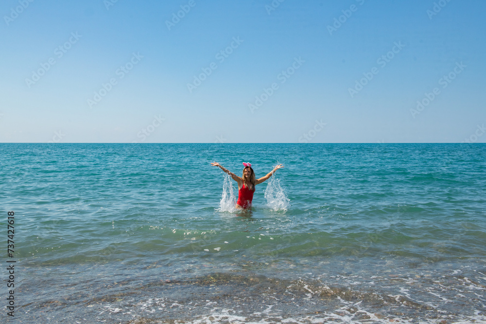 Santa Hat Waves: Girl in Red Swimsuit Embraces the Sea